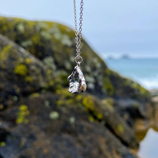 Imagine a stunning sterling silver pendant inspired by the sea, featuring a natural texture and charming organic shape. Crafted by pouring molten silver into the sea, its unique form captures the essence of ocean waves. As sunlight dances upon it, the pendant comes alive, showcasing its intricate details and textures. Picture it photographed on a picturesque beach in Cornwall, close to where it was lovingly created.